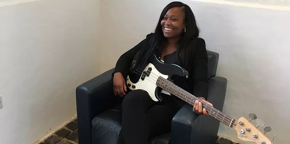 Young woman sitting playing a bass guitar